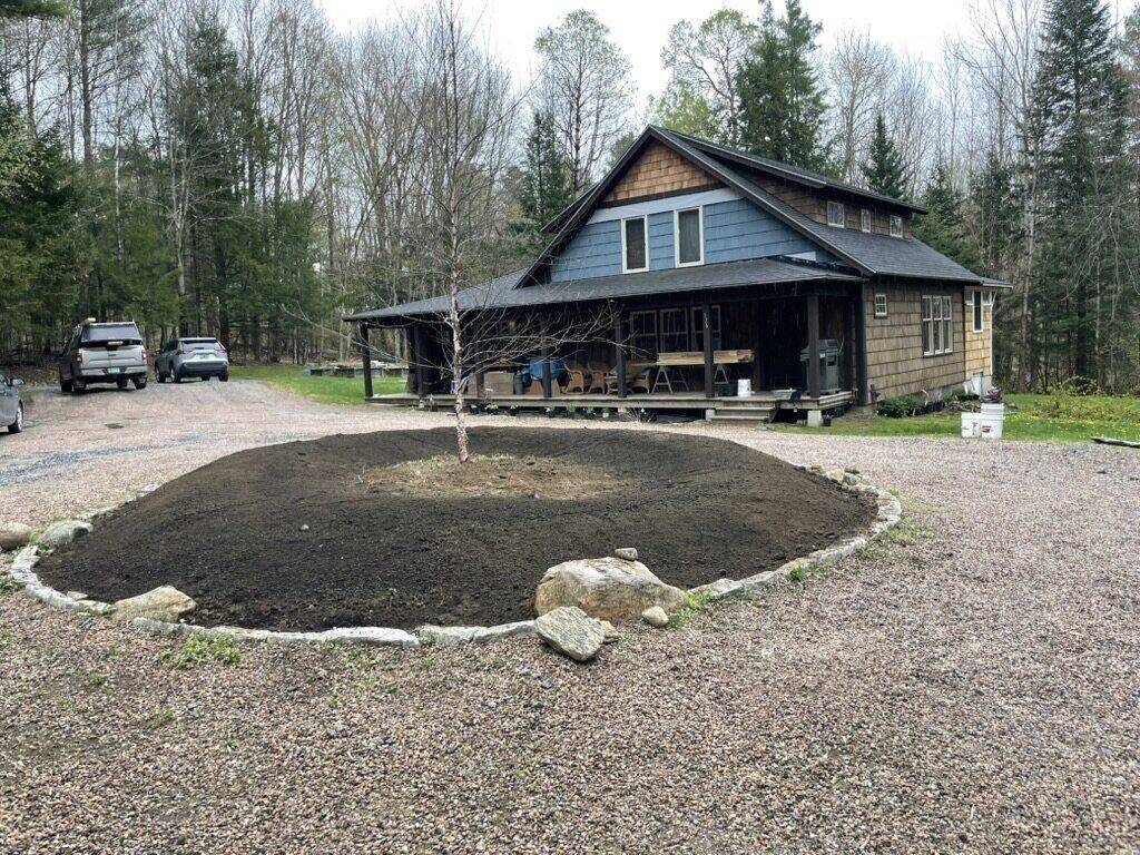 The circle regraded with fresh soil, mounded inside the stone edge